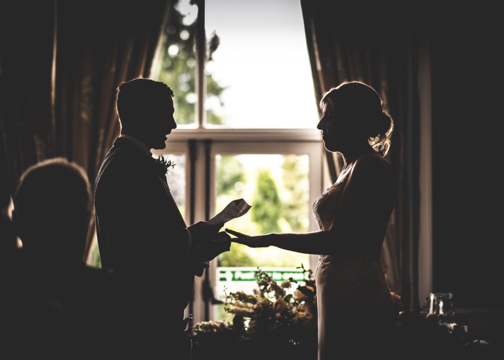 Silhouette of couple exchanging wedding rings
