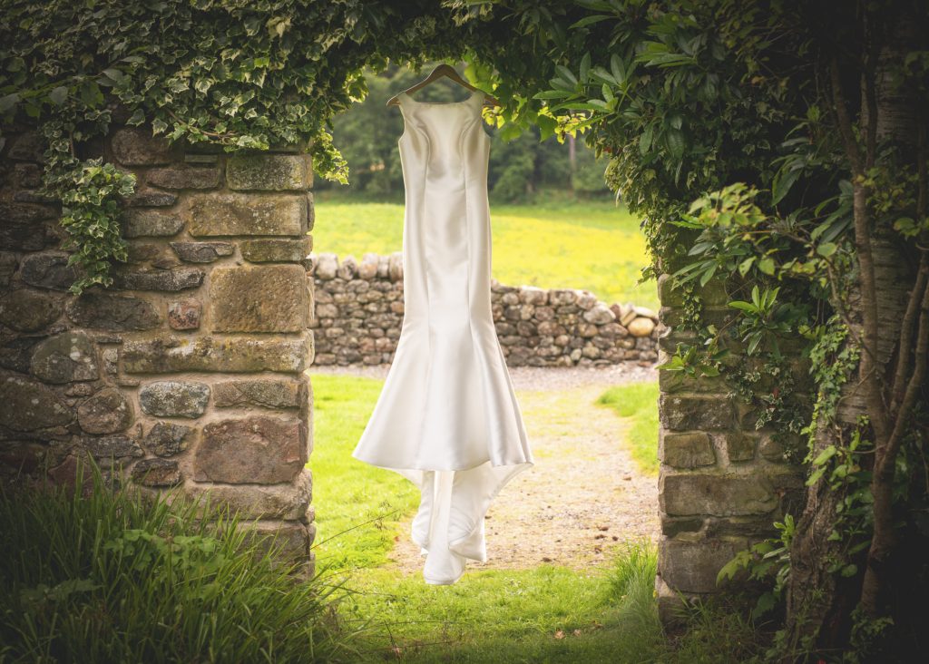 Wedding dress hanging in stone wall doorway