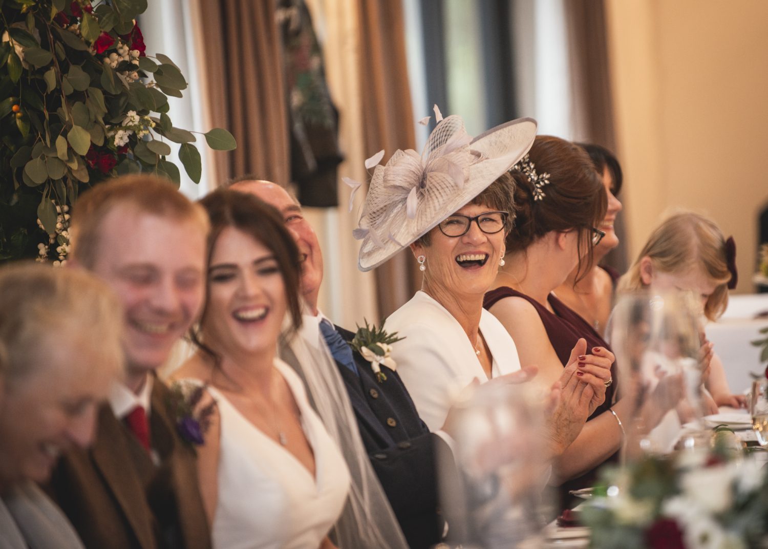 Mother of the bride laughing at top table during speeches at Loch Ness Country House Hotel wedding speeches