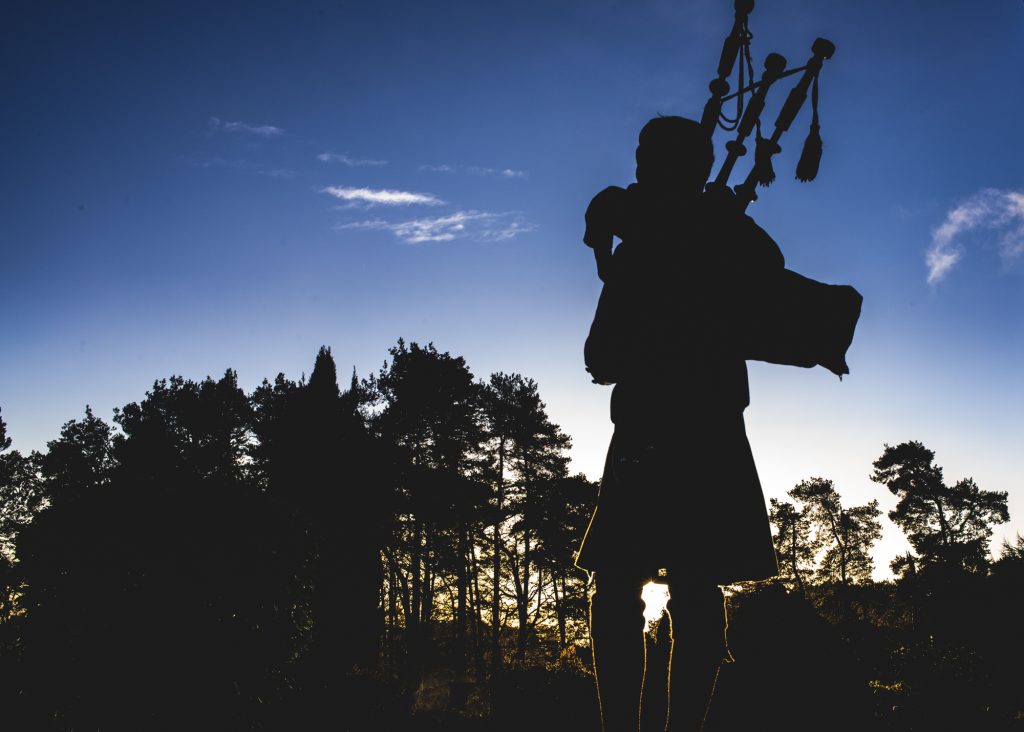 Silhouette of piper in kilt outside Loch Ness Country House Hotel