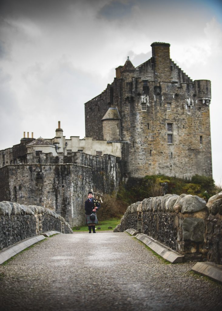 A piper plays outside Eilean Donan Castle