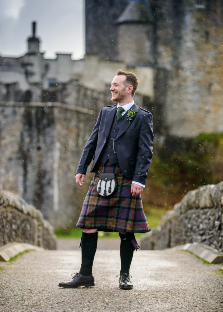 The groom stands for some photos in his kilt in front of Eilean Donan Castle