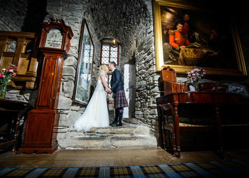 Bride and groom kiss in a stone porch window
