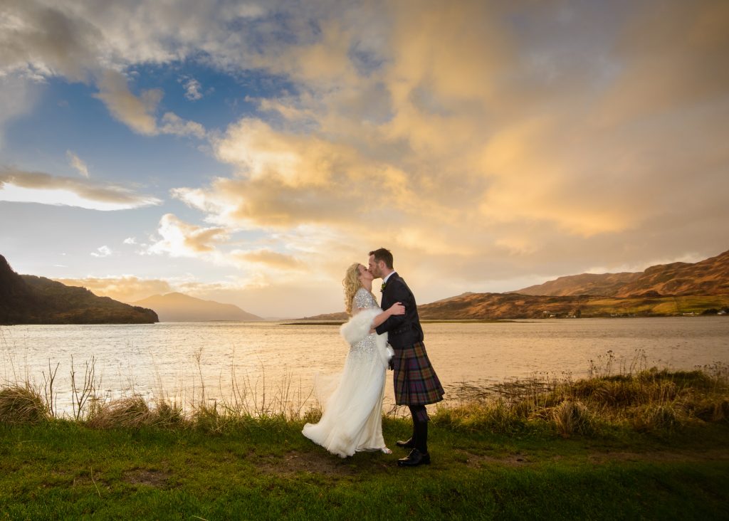 Married couple standing by the shores of Loch Shiel at dusk