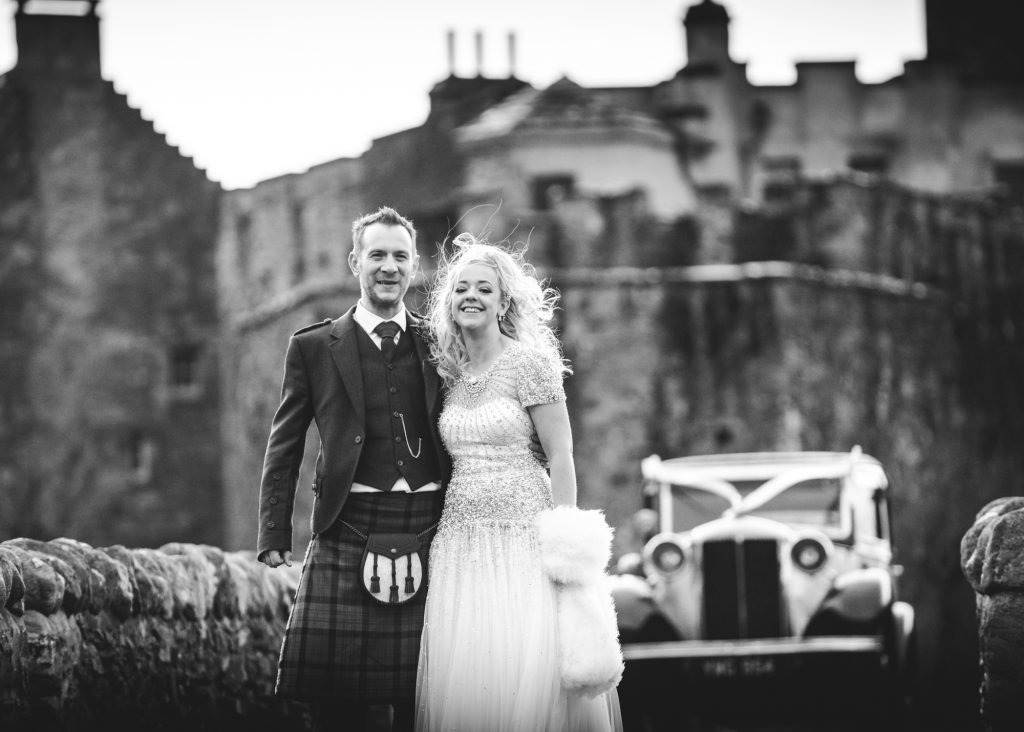 Wedding couple with wedding car in background at Eilean Donan Castle Wedding
