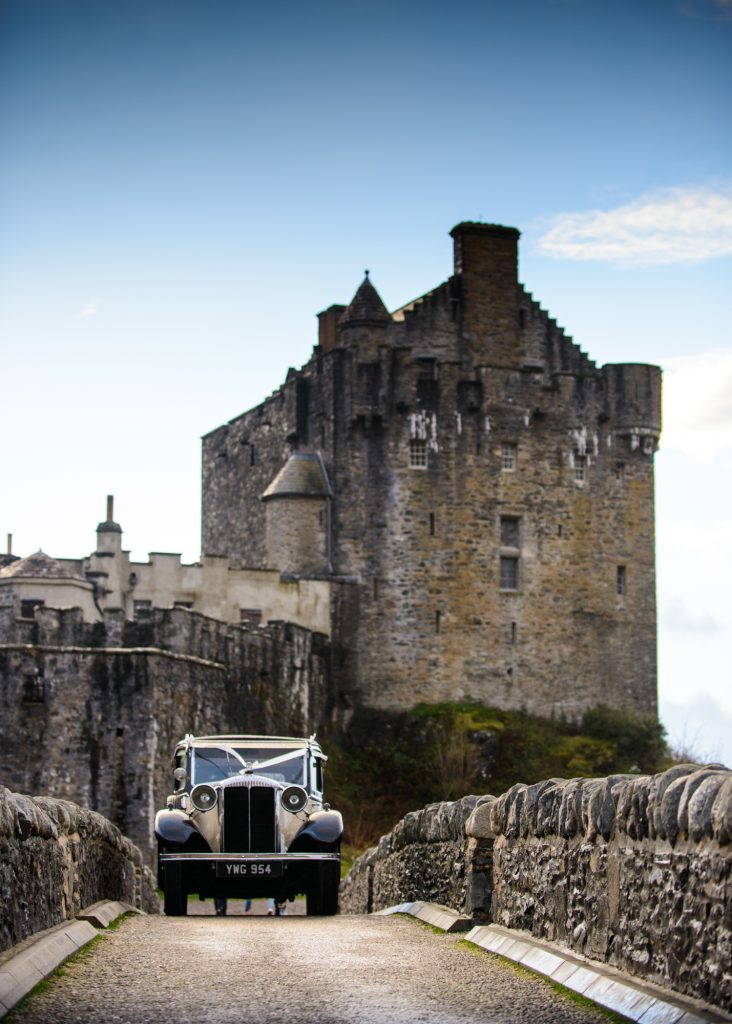 Vintage wedding car parked on bridge outside castle