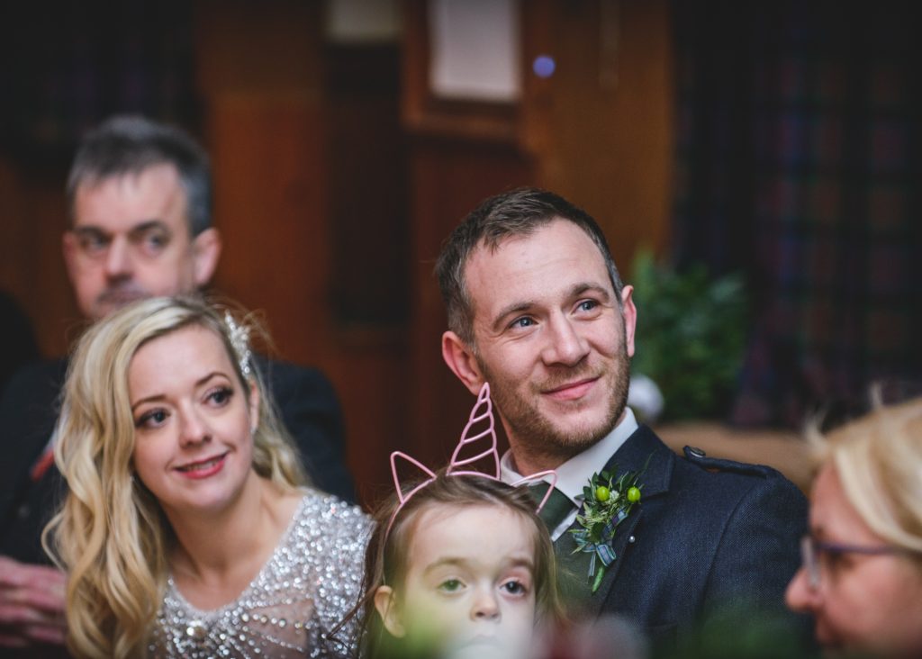 Bride and groom watching on during wedding speeches